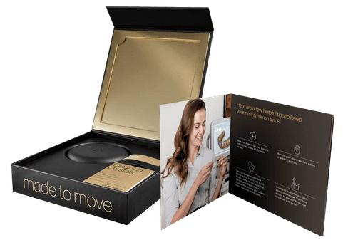 Branded dental marketing box set with open compartments, product samples, and informational leaflets displayed.