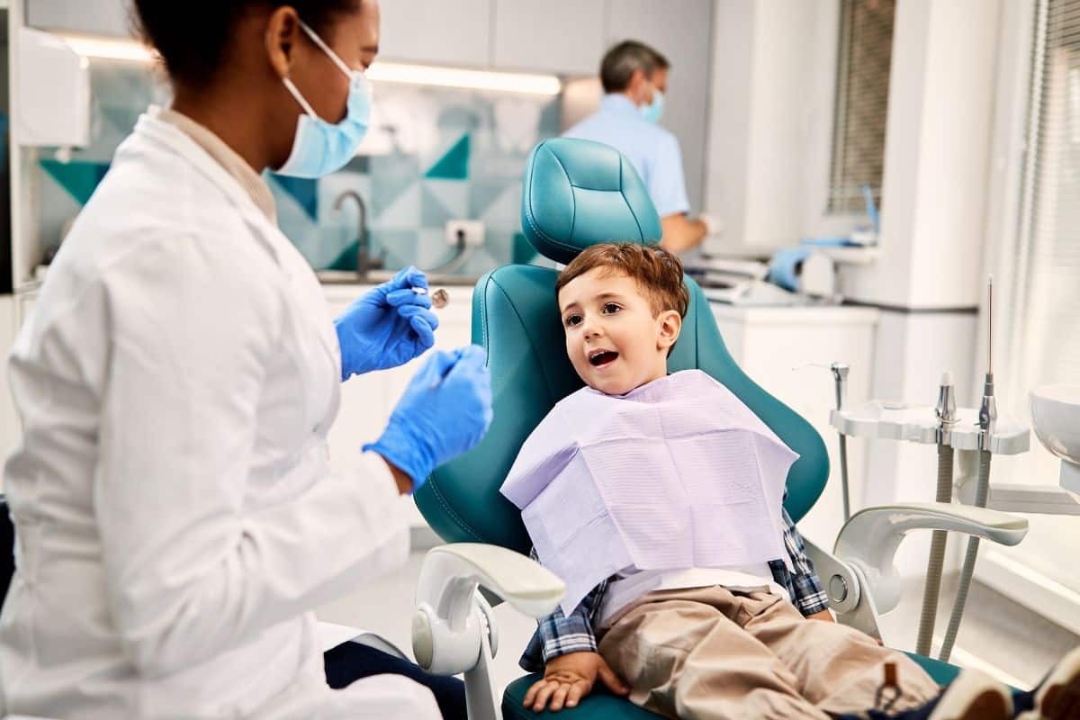 Young child sitting in dental chair during first dental visit with pediatric dentist.