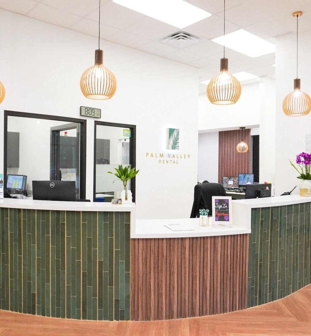 Palm Valley Dental reception area with curved desk, green tile accents, and wooden pendant lighting in Edinburg.